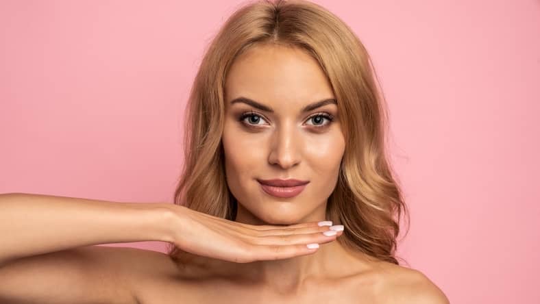 woman holding her hand under her chin after chin augmentation surgery