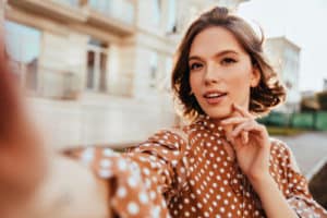 glamorous woman in brown attire making selfie.